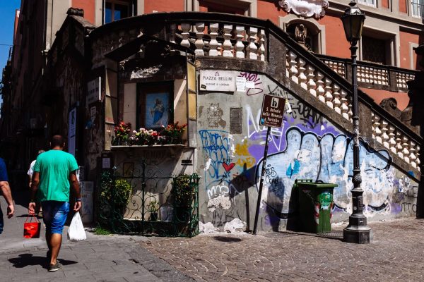 HISTORIC CITY CENTRE, NAPLES, CAMPANIA, ITALY - 2017/08/10: Men walking by a religious shrine in Piazza Bellini in the old city of Naples. (Photo by Raquel Maria Carbonell Pagola/LightRocket via Getty Images)